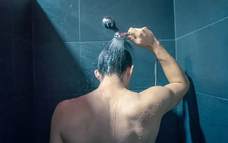 Hình ảnh một người đang tắm vòi sen với làn hơi nước nhẹ.